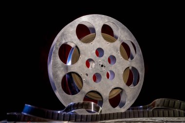 35 mm film reel with dramatic lighting on a dark background clipart