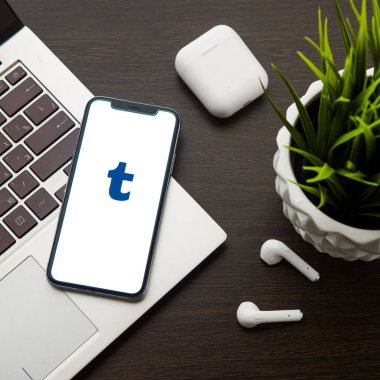 iphone X ekranındaki Tumblr logosu Airpods'un yanındaki dizüstü bilgisayar klavyesine yerleştirilir.