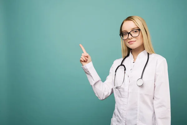 Stetoskop copyspase işaret gülümseyen genç tıp doktoru kadın. — Stok fotoğraf