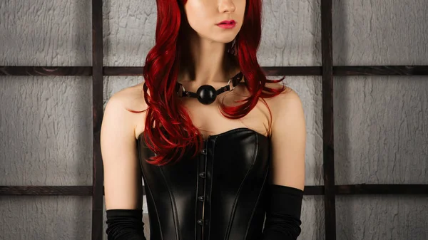 Portrait of Red-haired girl in a leather corset with gag ball — Stock Photo, Image