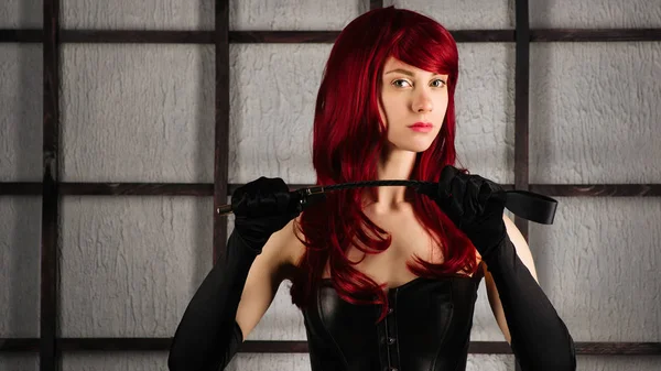 Deri korse kızıl saçlı kız şaplak tutar.