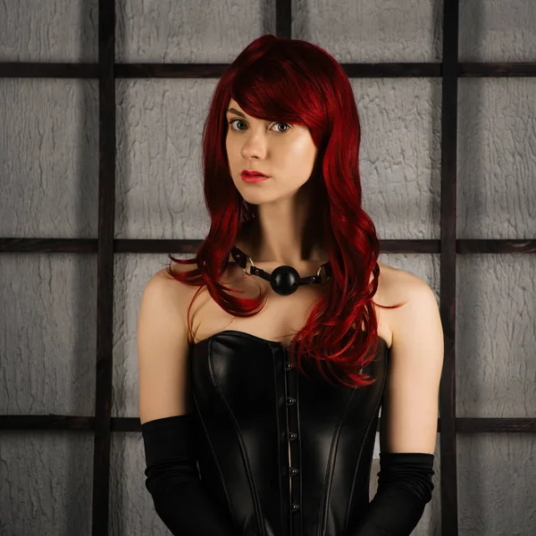 Portrait of Red-haired girl in a leather corset with gag ball — Stock Photo, Image