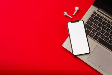 Tula, Rusya - 24 Mayıs 2019: Dizüstü bilgisayarlı kırmızı arka plan da Apple iphone X ve Airpods.