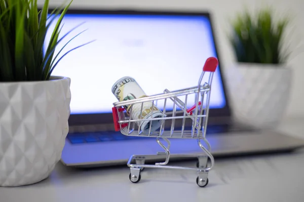 Conceito de compras online. Um carrinho com dinheiro está no teclado de um laptop . — Fotografia de Stock