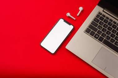 Tula, Rusya - 24 Mayıs 2019: Dizüstü bilgisayarlı kırmızı arka plan da Apple iphone X ve Airpods.
