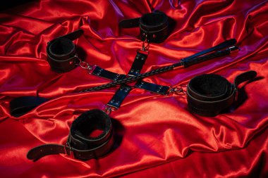 BDSM kıyafeti üst görünümü. Kırmızı keten üzerinde esaret ve şaplak. Yetişkin Seks Oyunları. Kinky yaşam tarzı.