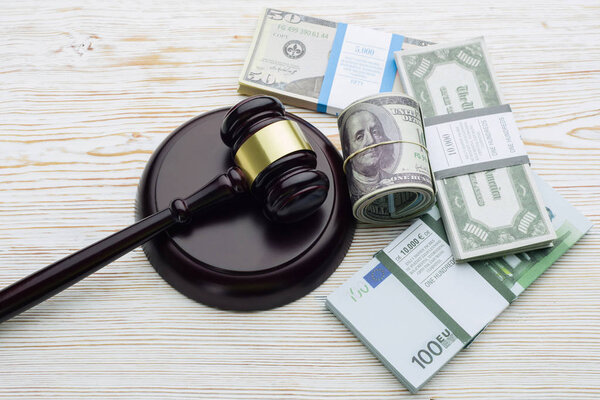 Top view Judge's gavel and packs of dollars and euro banknotes on a white wooden table