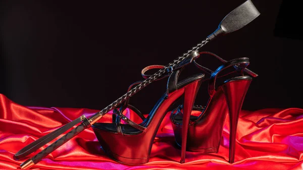 Yetişkin Seks Oyunları. Sapıkça yaşam tarzı. Spank ve kırmızı keten üzerinde siyah yüksek topuklu ayakkabı bir çift. BDSM kıyafeti