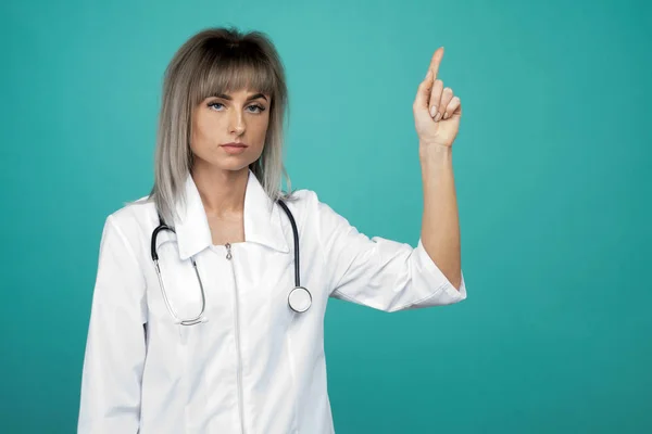 Bir stetoskop ile gülümseyen genç kadın doktor parmaklarını yukarı puan — Stok fotoğraf
