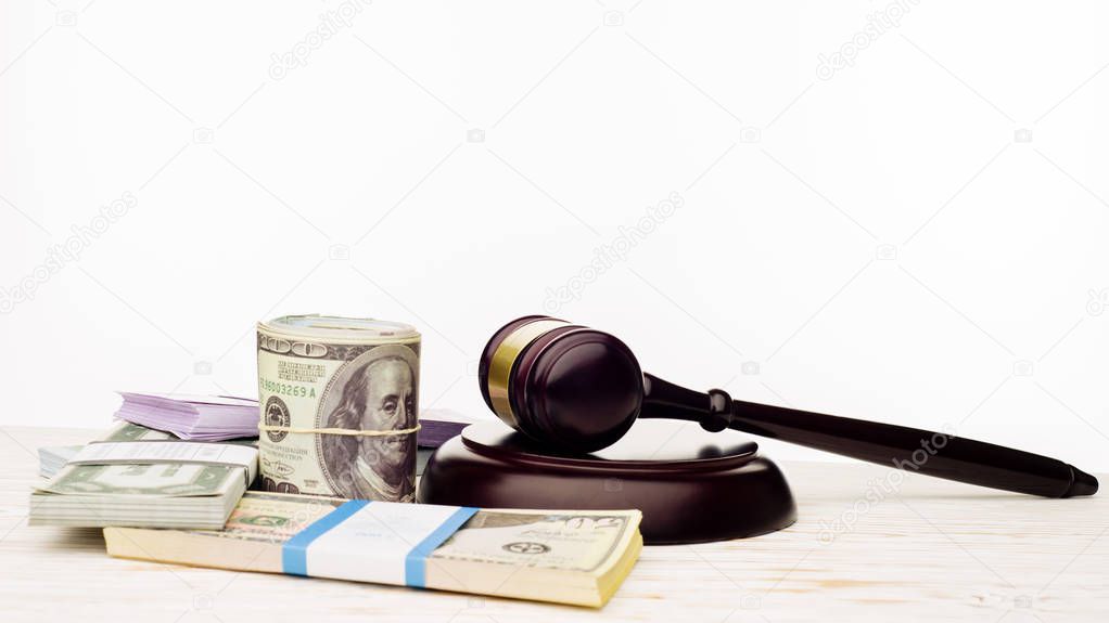 Judge's gavel and packs of dollars and euro banknotes on a white wooden table
