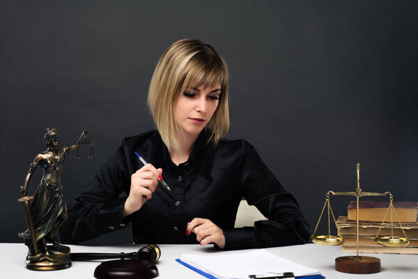A young fair woman judge works in her office.