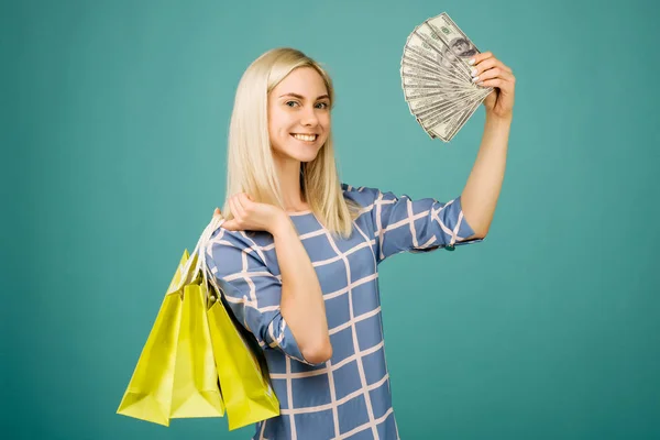 Lycklig tjej i en rutig blus rymmer 100 dollar räkningar och shoppingväskor — Stockfoto