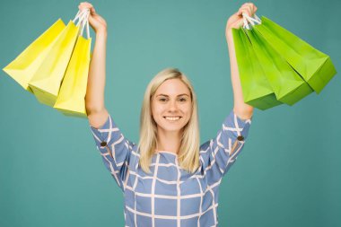 Damalı bluzlu mutlu kız alışveriş çantaları tutar
