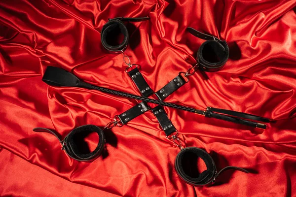 stock image Top view of bdsm outfit. Bondage and spank on the red linen. Adult sex games. Kinky lifestyle.