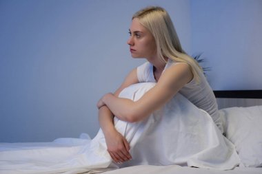 Sad yatağında gece geç saatlerde oturan kadın depresif, dalgın ve uykusuzluk acı bir kız