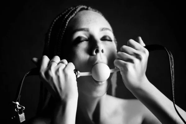 BDSM roupa para jogos de sexo para adultos. Uma jovem mulher lambe a bola de mordaça. Preto e branco — Fotografia de Stock