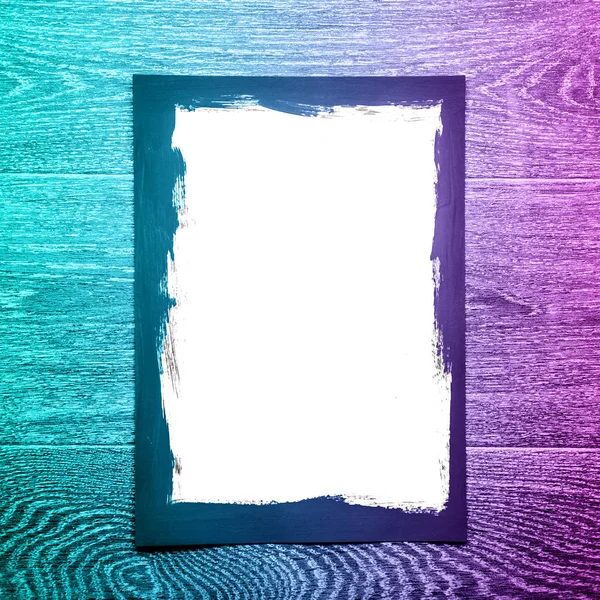 Černý malovaný rámeček na bílém papíře na dřevěném pozadí s neórovým světlem — Stock fotografie