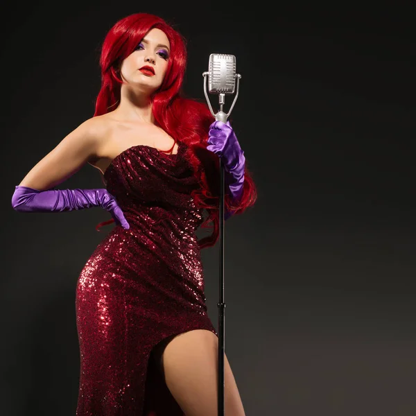 Jonge redhead vrouw retro stijl zanger. Vintage microfoon en donkere achtergrond — Stockfoto