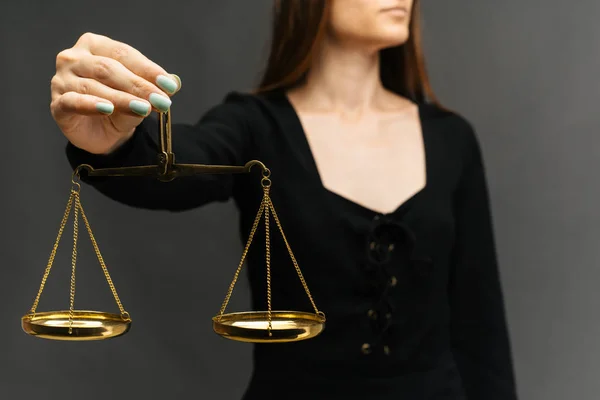 Serious woman holding the justice scale on dark background