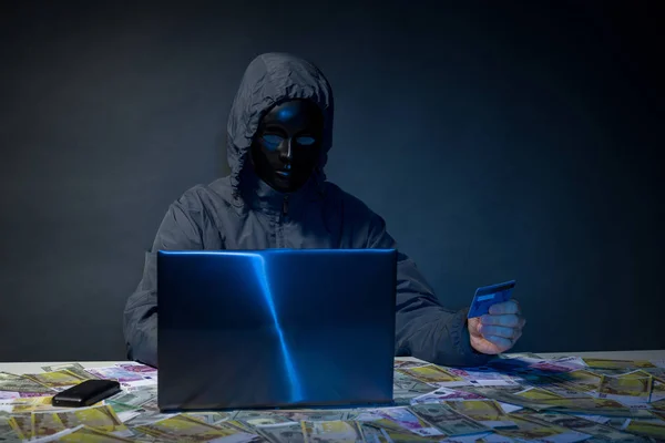 Hacker anônimo no programador máscara usa um laptop para hackear o sistema no escuro . — Fotografia de Stock