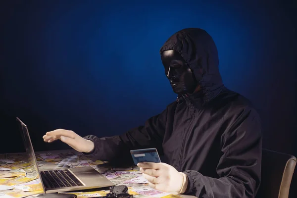 Anonieme hacker in Mask programmeur maakt gebruik van een laptop om het systeem te hacken in het donker. — Stockfoto