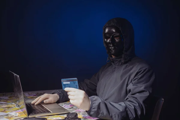 Anonyme Hacker in Maske Programmierer verwendet einen Laptop, um das System im Dunkeln zu hacken. — Stockfoto