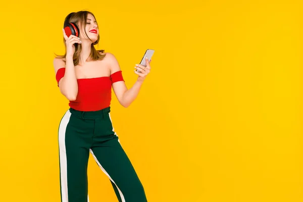 Hermosa joven en auriculares escuchando música sobre fondo amarillo — Foto de Stock