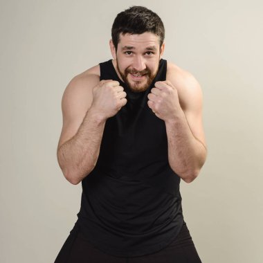 Dövüşçü gri bir sırta karşı ön koruyucu poz veriyor.