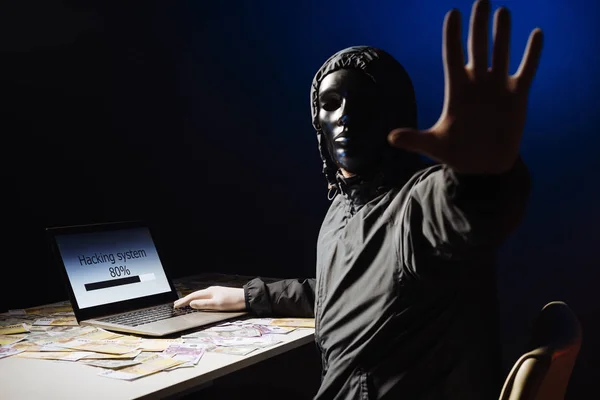 Programador de hackers anônimo usa um laptop para hackear o sistema no escuro. Criação e infecção de vírus malicioso. O conceito de cibercrime e base de dados de pirataria — Fotografia de Stock