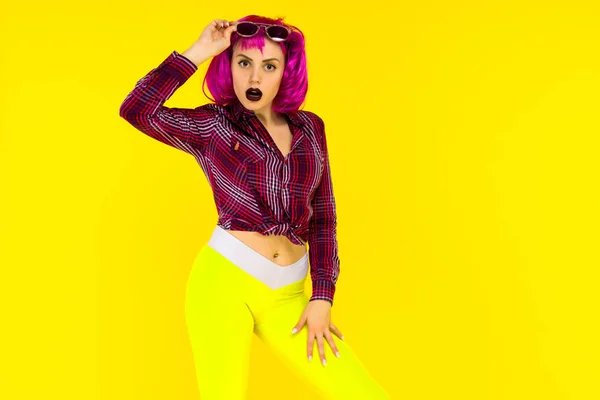 Retrato de chica impactada sobre fondo amarillo. Mujer joven de estilo loco en peluca rosa — Foto de Stock