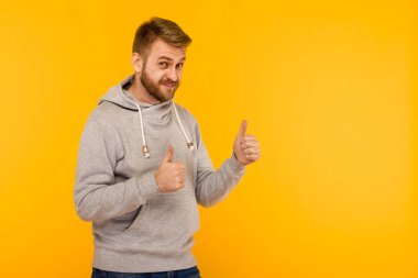 Sarı backgr üzerinde gri kapüşonlu Yakışıklı çekici Avrupalı adam