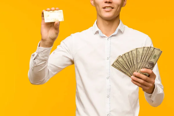 Porträtt av Happy Young Asian man Holding kreditkort och pengar i hand leende och tittar på kamera — Stockfoto