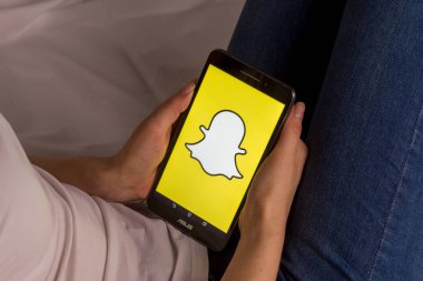 Tula, Rusya, 17 Eylül 2019: Asyalı kız yatakta yatıyor ve ekranda Snapchat logosu olan bir tablet tutuyor.
