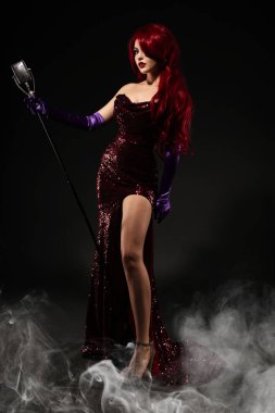 Genç Kızıl saçlı kadın retro tarzı şarkıcı. Vintage mikrofon ve koyu arka plan