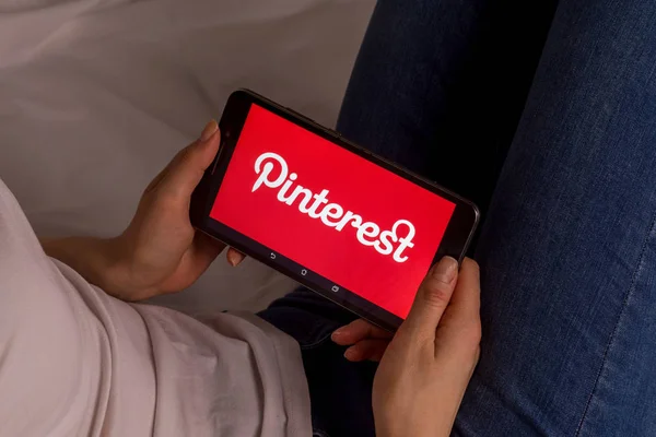 Tula, Rusia, 17 de septiembre de 2019: Chica asiática se acuesta en la cama y sostiene una tableta con el logotipo de Pinterest en la pantalla . — Foto de Stock