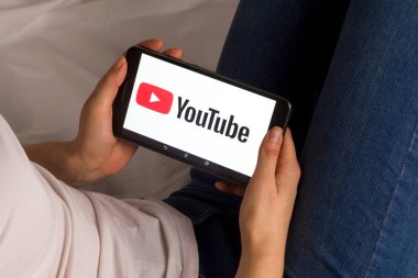Tula, Rusya, 17 Eylül 2019: Asyalı kız yatakta yatıyor ve ekranda Youtube logosu olan bir tablet tutuyor.
