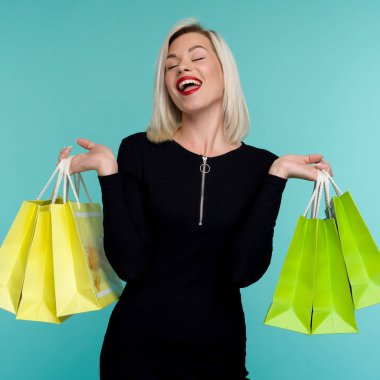 Siyah Cuma tatilinde alışveriş poşetleri tutan genç gülümseyen kadın. Mavi arka planda Happy Girl