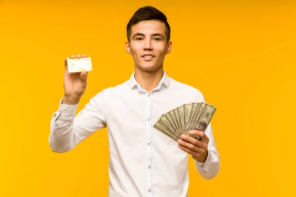 Porträtt av Happy Young Asian man Holding kreditkort och pengar i hand leende och tittar på kamera — Stockfoto