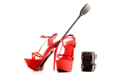 Yetişkin seks oyunları için Bdsm kıyafeti. Kırmızı yüksek topuklu striptiz ayakkabı ve kelepçe, beyaz bir arka plan üzerinde izole kırbaç