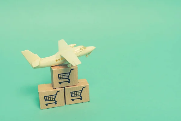 White model airplane lands on blue background from most famous countries around the world with boxes of goods behind. An idea of air freight transportation, global parcel forwarding, international shipping