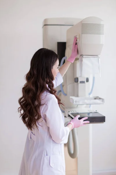 彼女のクリニックで超音波検査 乳房の超音波検査装置を準備しているピンクの手袋で若い元気な乳がんの専門家の側面図 — ストック写真