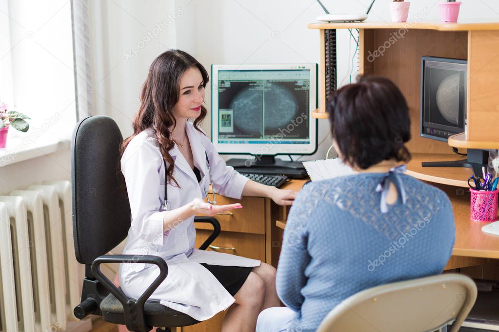The young happy breast specialist talking with the patient in her office