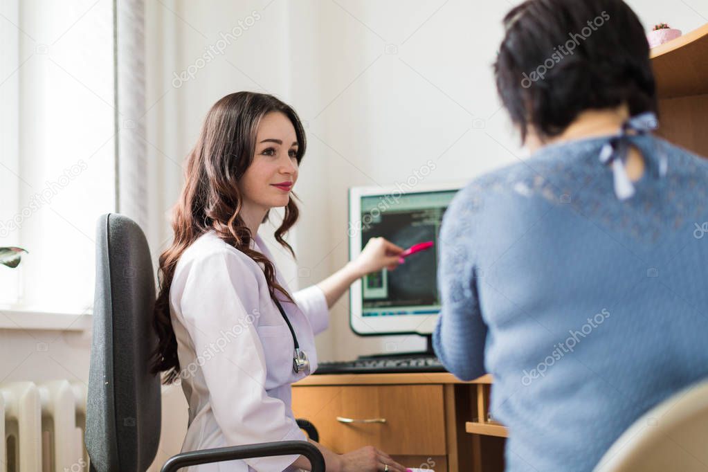 The young happy breast specialist showing the ultrasound examination to the patient in her office