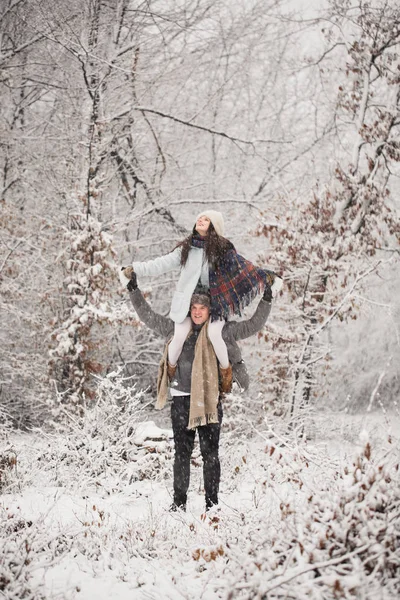 年轻人抱着肩膀 他快乐的妻子在雪覆盖的公园 — 图库照片