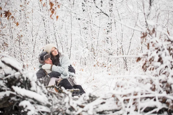 快乐的年轻人坐在白雪覆盖的公园里 抱着快乐 美丽的女人在膝上 — 图库照片