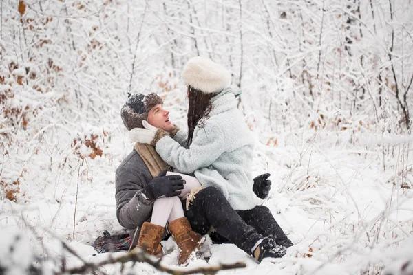 那位快乐的年轻人坐在白雪覆盖的公园里 抱着年轻女子在膝上 他们互相看着对方 — 图库照片