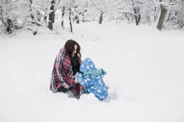 年轻开朗的母亲在白雪覆盖的公园里和她可爱的小儿子玩耍 — 图库照片