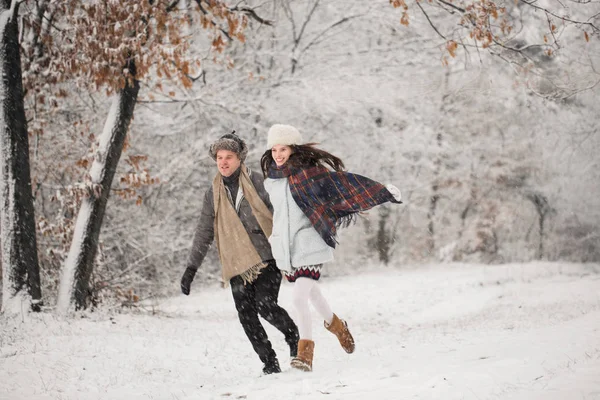 在户外雪覆盖的公园里奔跑的年轻快乐情侣 — 图库照片