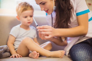 Genç hemşire olan şirin küçük çocuk odasında kanepede oturan ve şırınga tutarak portresi