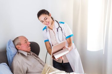 Yaşlı, hasta bir yatak ve Genç neşeli Doktor onun yanında ayakta yalan ve tablet onun odaya gösteren adam